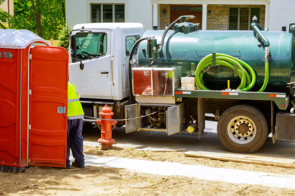 Septic pump truck with hose emptying a residential tank on site